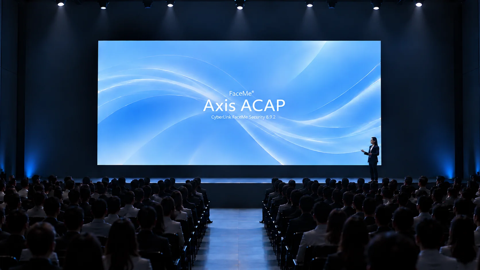 Un presentatore sul palco di fronte a un grande schermo blu con la scritta FaceMe Axis ACAP, il pubblico seduto